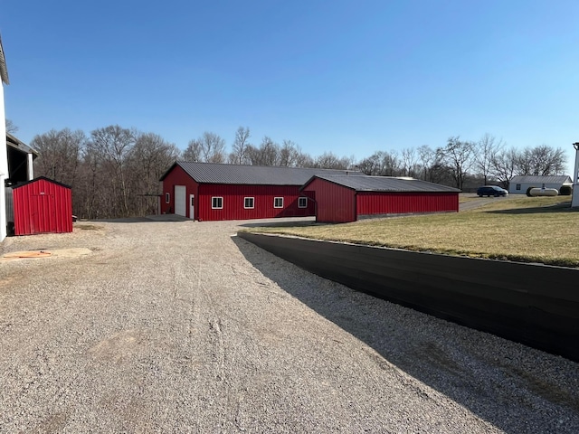 exterior space with a yard, gravel driveway, an outdoor structure, and a pole building