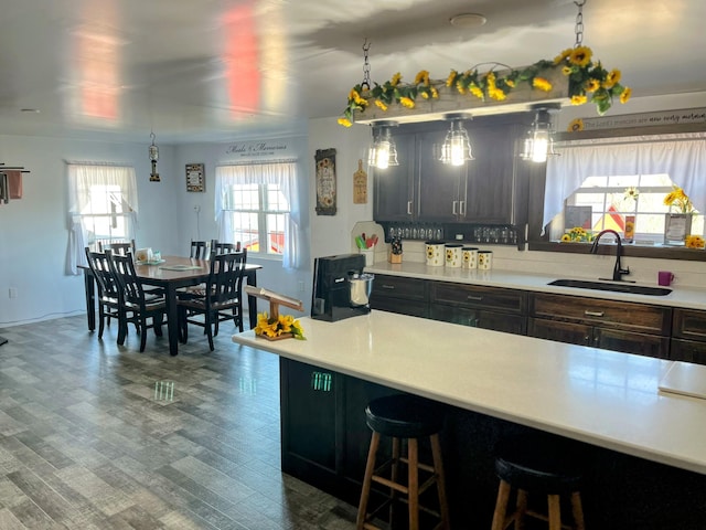 kitchen featuring backsplash, light countertops, a kitchen bar, and a sink