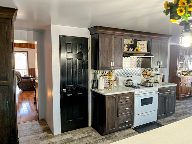 kitchen with white gas stove, dark brown cabinetry, light wood finished floors, and light countertops