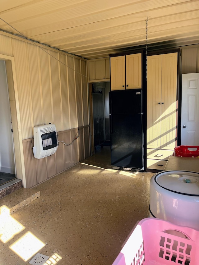 kitchen featuring heating unit, metal wall, speckled floor, and freestanding refrigerator