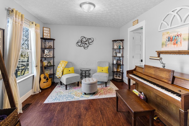 sitting room with visible vents, baseboards, a textured ceiling, and dark wood-style flooring