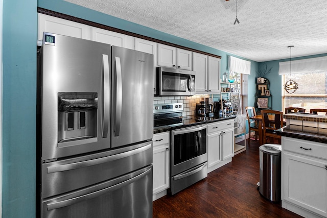 kitchen with dark countertops, appliances with stainless steel finishes, white cabinetry, and dark wood-type flooring