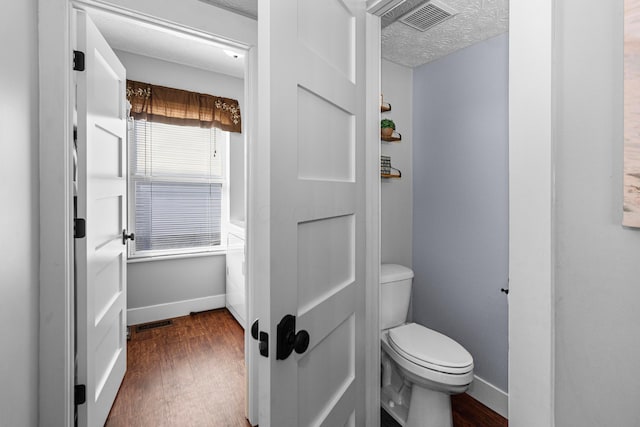 bathroom with visible vents, baseboards, toilet, and wood finished floors