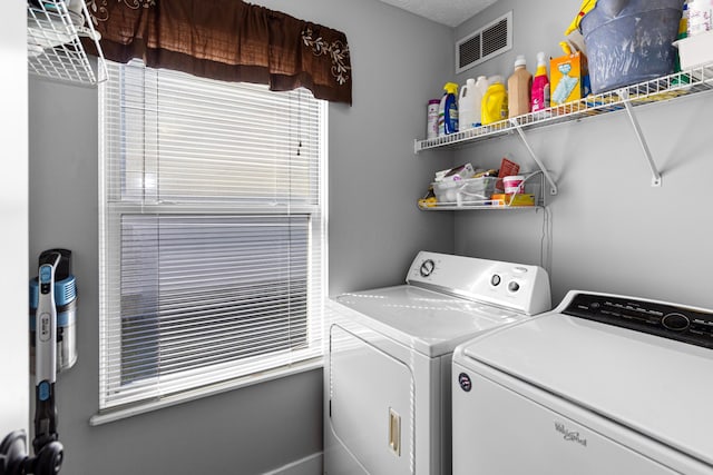 clothes washing area with visible vents, washing machine and dryer, and laundry area