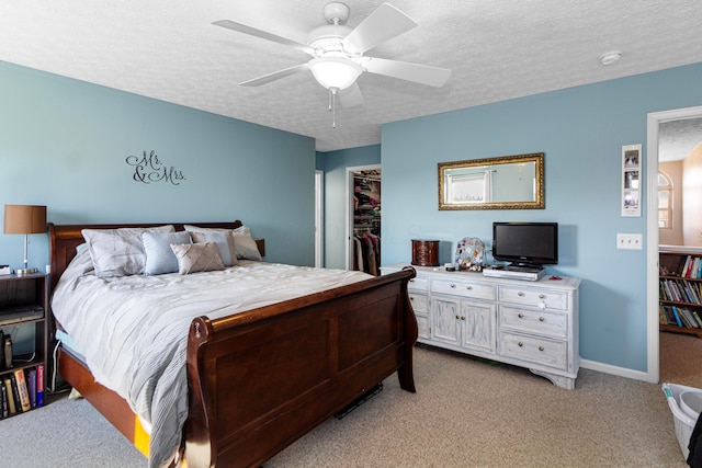 bedroom featuring a ceiling fan, a textured ceiling, a closet, light colored carpet, and a spacious closet