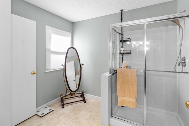 full bath featuring baseboards, a stall shower, and a textured ceiling