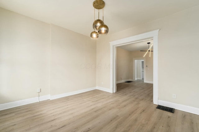 unfurnished room featuring visible vents, baseboards, and wood finished floors