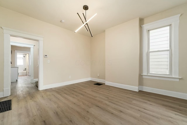 unfurnished dining area with a notable chandelier, baseboards, visible vents, and light wood-type flooring