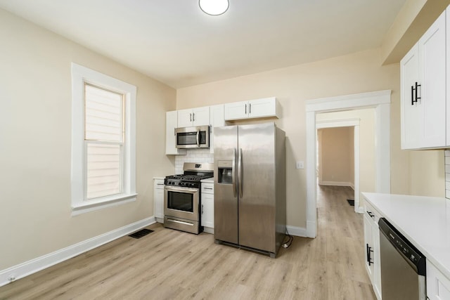 kitchen featuring visible vents, baseboards, decorative backsplash, appliances with stainless steel finishes, and white cabinetry