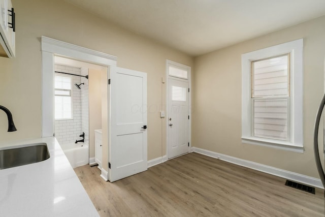 interior space featuring visible vents, baseboards, light countertops, light wood-style flooring, and a sink