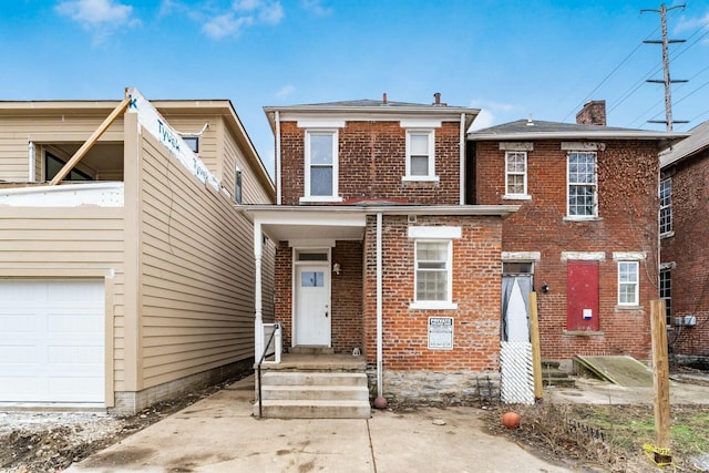 view of front of property with a garage, brick siding, and a chimney