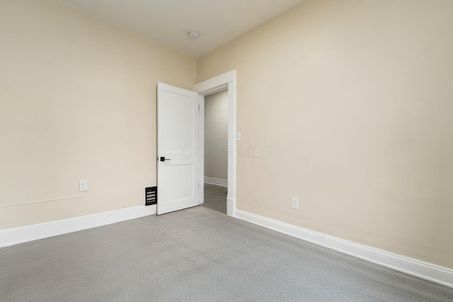 carpeted empty room featuring baseboards