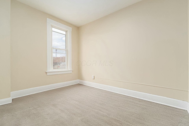 carpeted empty room featuring baseboards and vaulted ceiling