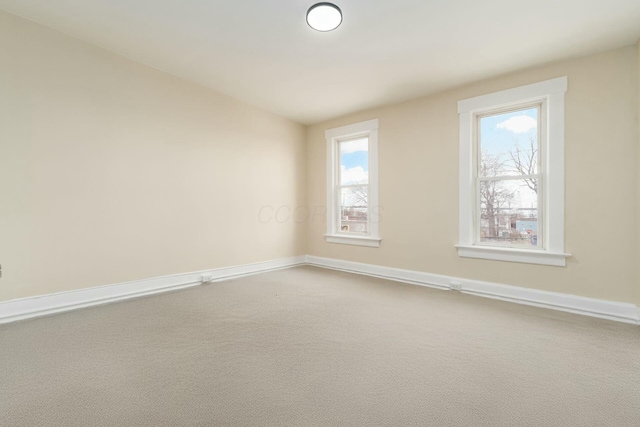 carpeted empty room featuring baseboards