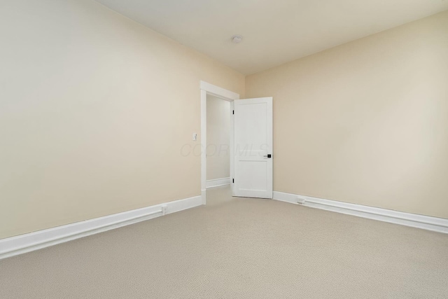 empty room featuring light colored carpet and baseboards