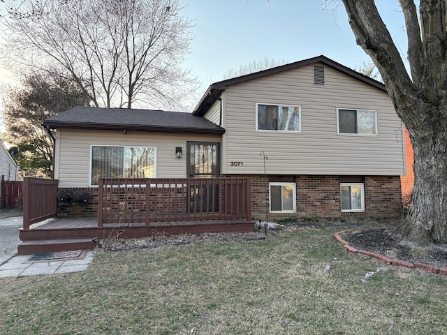 rear view of property with a yard, brick siding, and a wooden deck