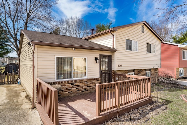 back of property featuring brick siding, roof with shingles, and a wooden deck