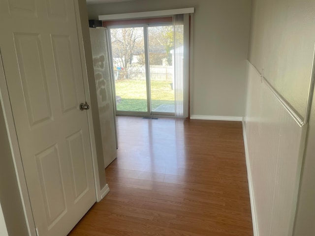 hallway with light wood-type flooring and baseboards