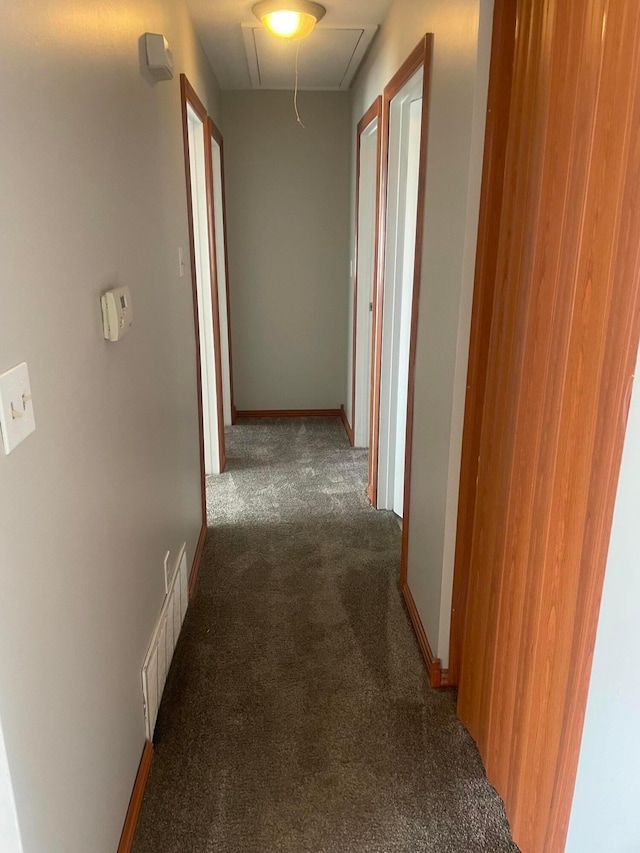 hall with baseboards, carpet flooring, attic access, and visible vents