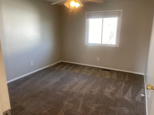 spare room with visible vents, a ceiling fan, baseboards, and dark colored carpet