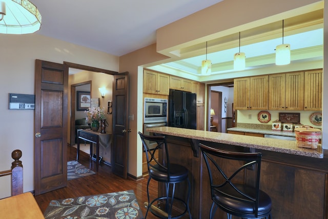 kitchen featuring a breakfast bar, a tray ceiling, a peninsula, dark wood-style floors, and black fridge with ice dispenser