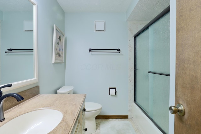 full bathroom featuring baseboards, toilet, vanity, shower / bath combination with glass door, and a textured ceiling