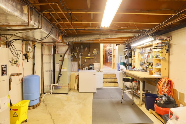 unfinished below grade area with a workshop area, water heater, and refrigerator