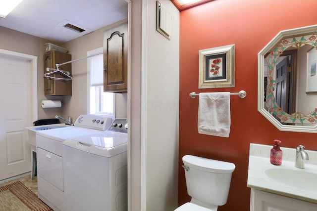 clothes washing area with a sink, visible vents, laundry area, and washing machine and clothes dryer