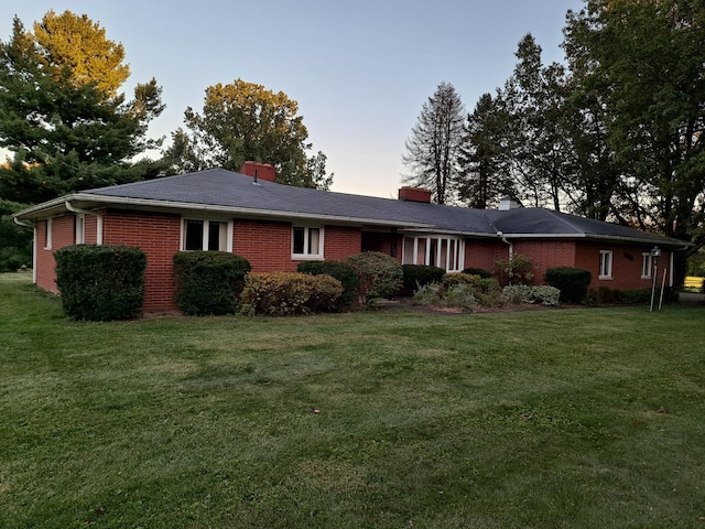 exterior space featuring a front yard, brick siding, and a chimney