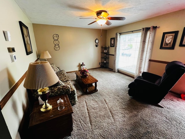 living area with a ceiling fan, baseboards, carpet floors, and a textured ceiling