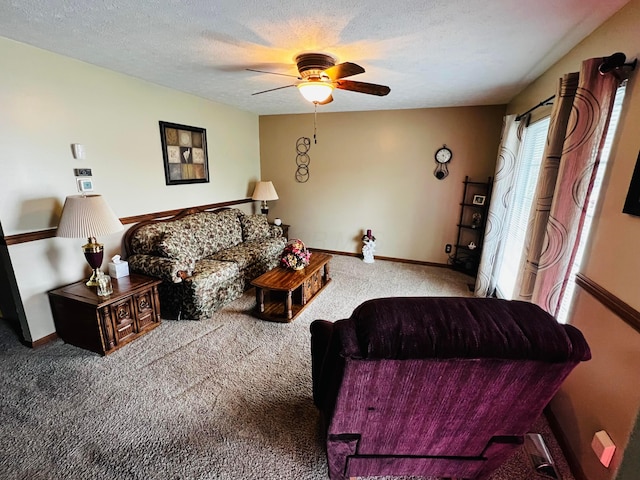 carpeted living area with baseboards, a textured ceiling, and ceiling fan