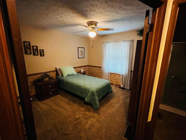 bedroom with a wainscoted wall, a textured ceiling, ceiling fan, and carpet flooring