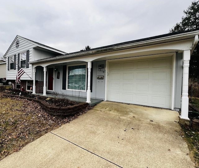 tri-level home featuring a porch, an attached garage, and concrete driveway