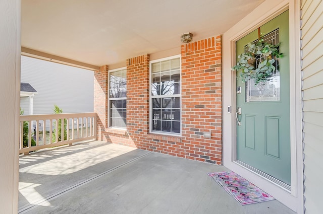 entrance to property with brick siding and a porch