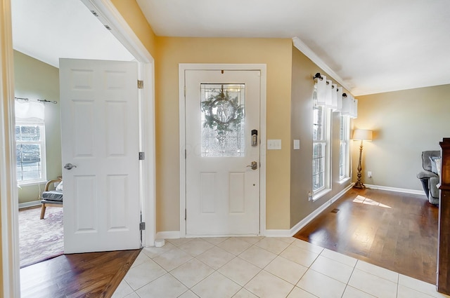 entryway with light tile patterned floors, baseboards, and ornamental molding