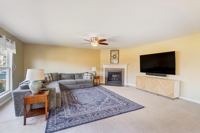 living room with baseboards, carpet, ceiling fan, and a tiled fireplace