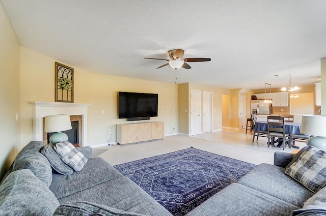 living area featuring baseboards, light carpet, and ceiling fan