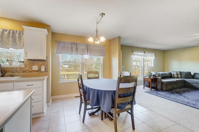 dining space with light tile patterned floors, light colored carpet, baseboards, and a chandelier