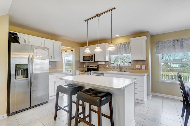 kitchen with light tile patterned flooring, a sink, stainless steel appliances, light countertops, and tasteful backsplash