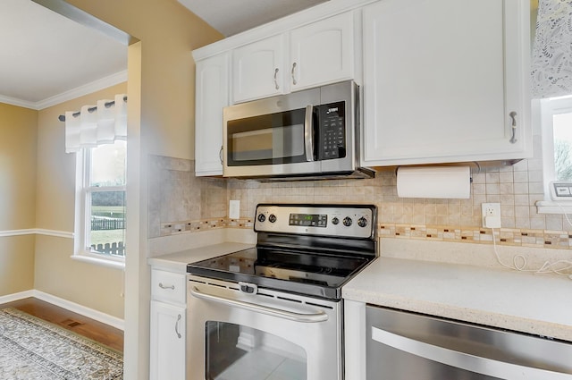 kitchen with white cabinetry, stainless steel appliances, crown molding, and light countertops