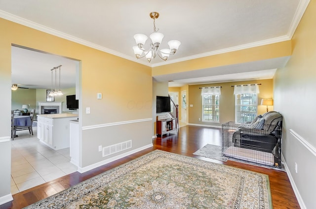 living room with a chandelier, visible vents, light wood-style flooring, and a fireplace