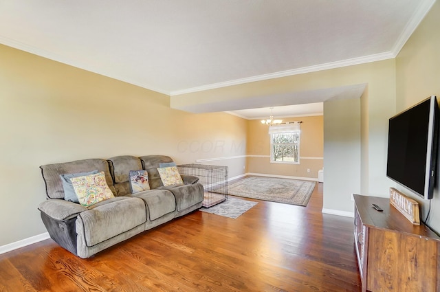 living room with a chandelier, ornamental molding, baseboards, and wood finished floors