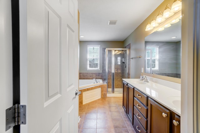 full bath with visible vents, double vanity, a stall shower, a sink, and tile patterned flooring