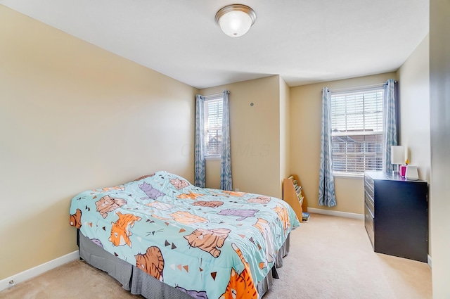 bedroom with multiple windows, light colored carpet, and baseboards