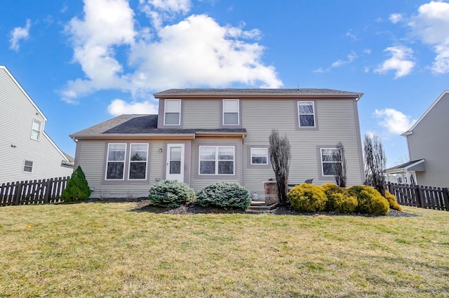 back of property with a lawn and fence