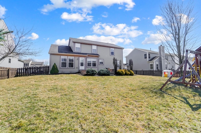 rear view of house featuring a lawn, a playground, and a fenced backyard