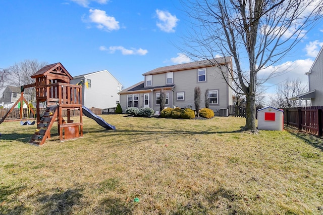 rear view of house with a storage unit, fence, a playground, a yard, and an outdoor structure