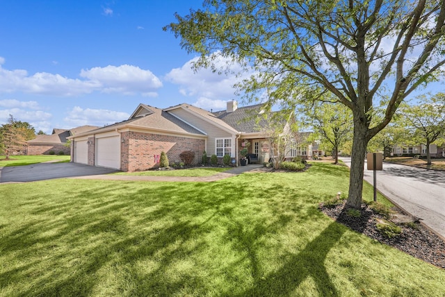 view of front facade featuring aphalt driveway, a front yard, an attached garage, brick siding, and a chimney