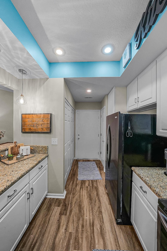 kitchen featuring light stone countertops, dark wood-style flooring, freestanding refrigerator, a textured ceiling, and white cabinetry