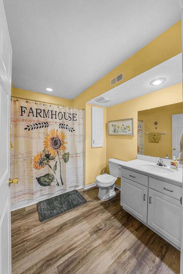 bathroom featuring visible vents, toilet, a shower with curtain, wood finished floors, and vanity